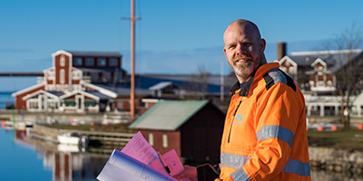 Leende kvinna som sitter och pratar med en annan person som man ser bakhuvudet på.