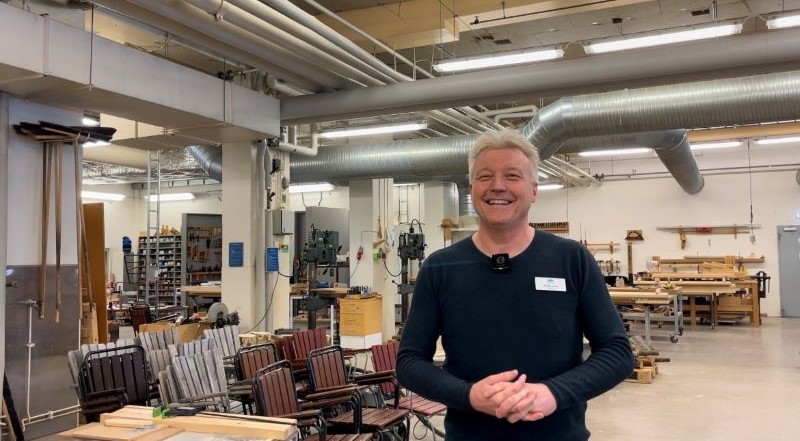 Leende man står i snickeri. Foto.