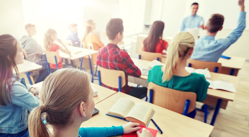 Elever sitter i bänkar i ett klassrum. Foto.