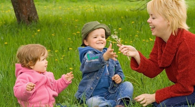 kvinna med två barn sitter i gräset